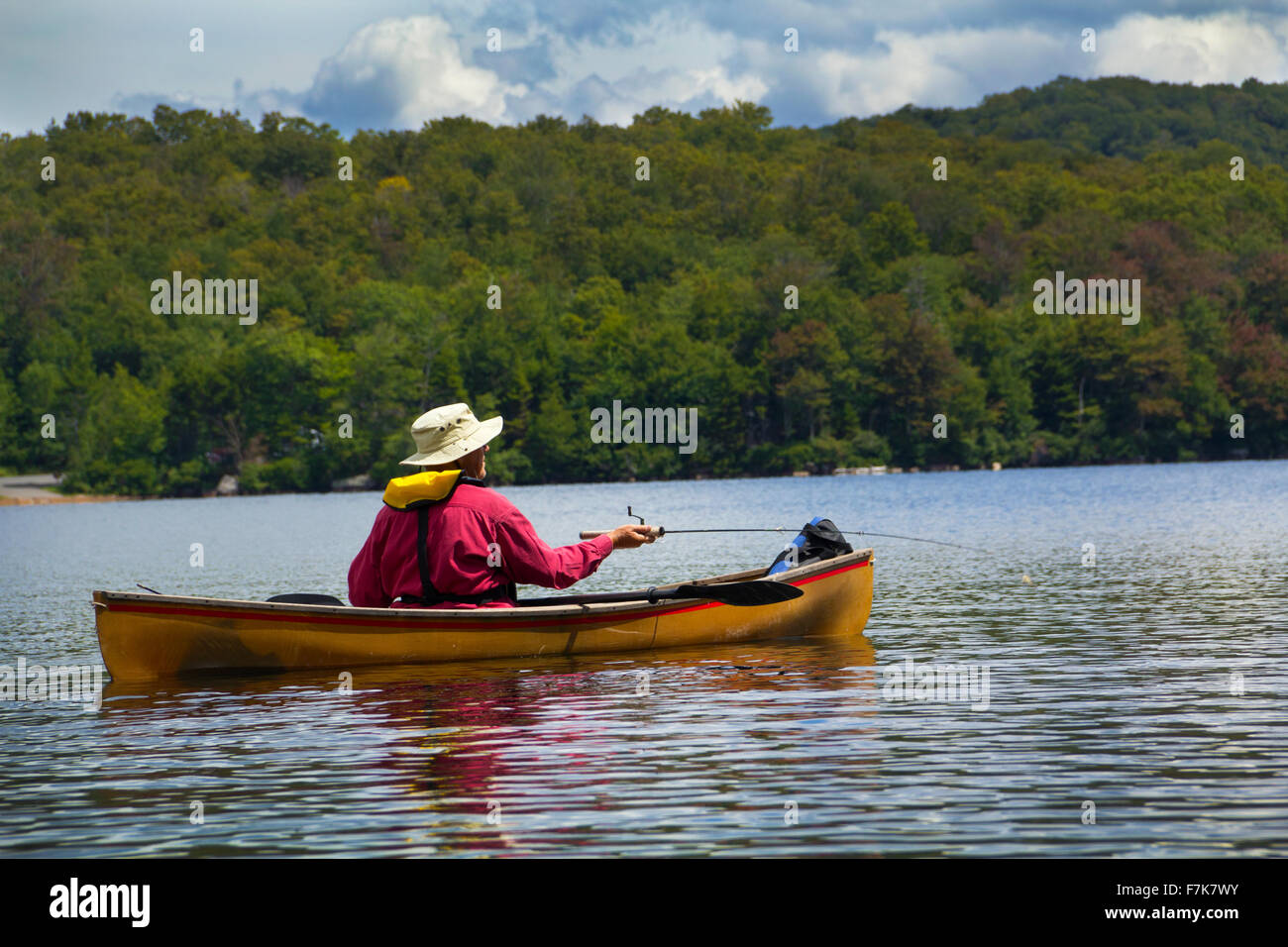 Senior man fishing from a small canoe on Limekiln Lake in Old