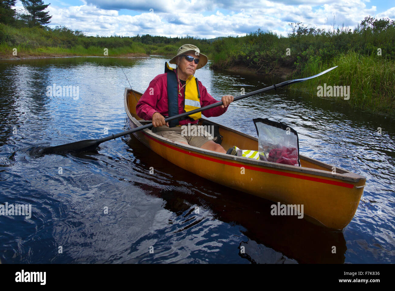 Senior man in an outdoor activity, paddling a small canoe with a kayak paddle on the Moose River near Old Forge, New York. Stock Photo