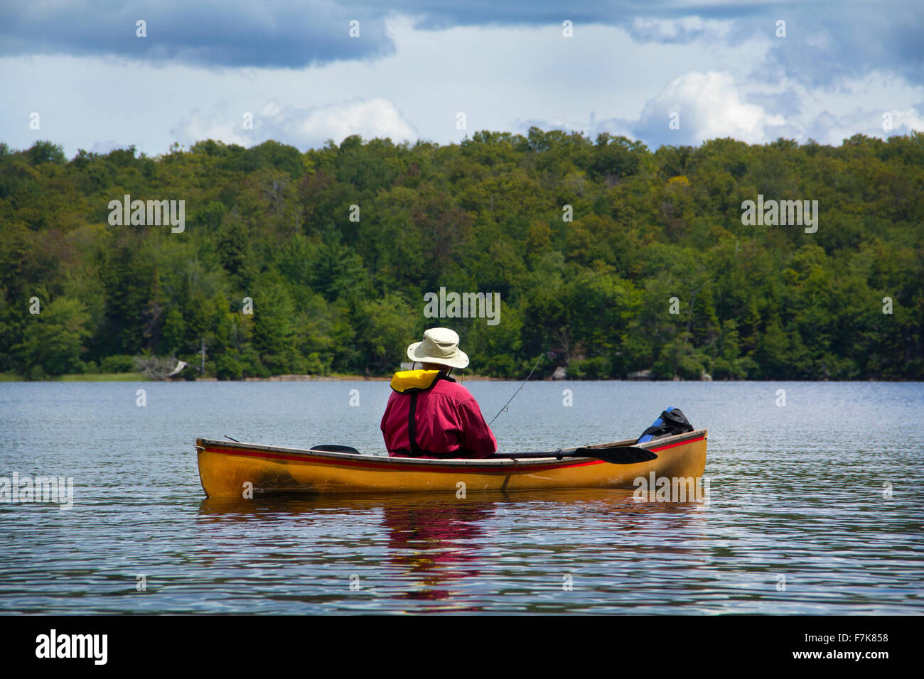 Senior man fishing from a small canoe on Limekiln Lake in