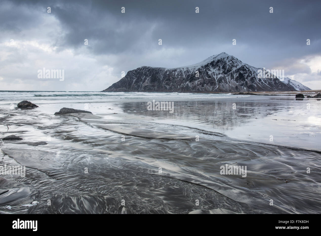 Snow covered rock formation on cold ocean beach, Skagsanden Beach, Lofoten Islands, Norway Stock Photo