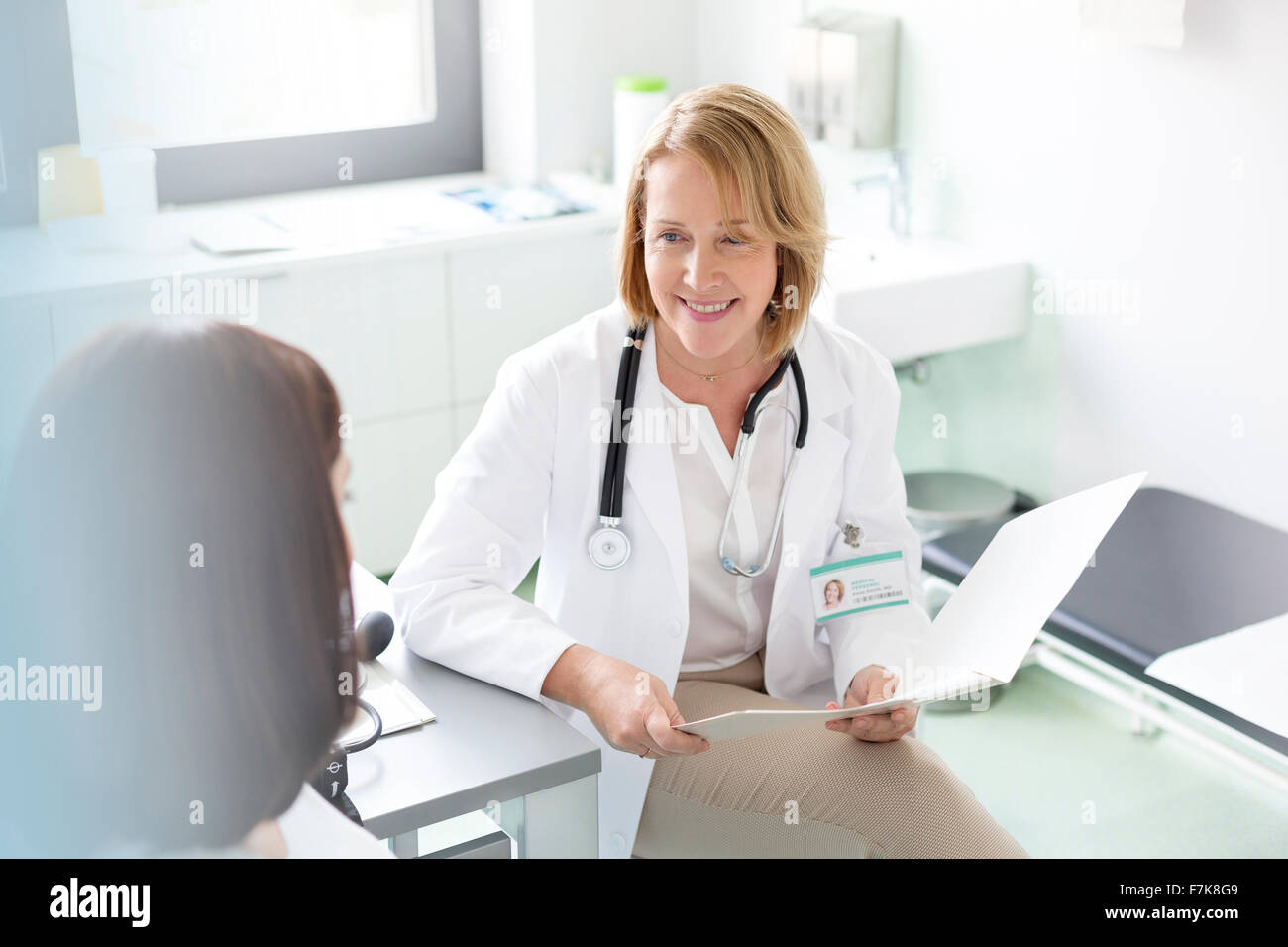 Doctor with medical chart talking with patient in examination room Stock Photo