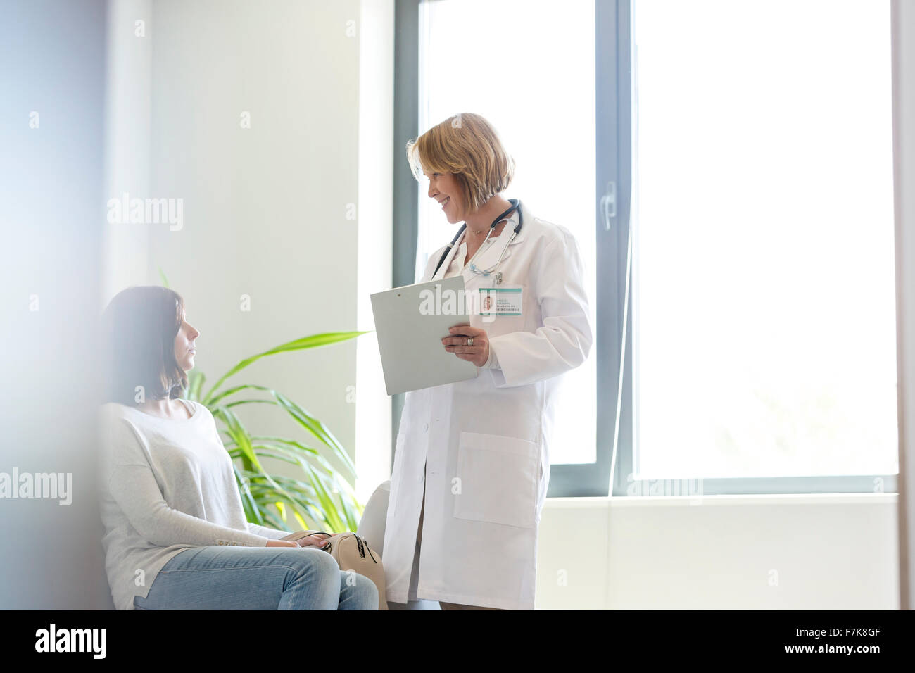 Doctor with medical record talking to patient in waiting room Stock Photo