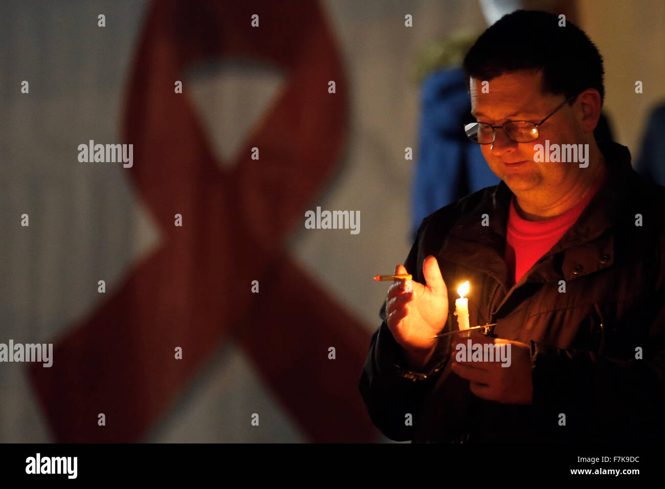 Brighton, UK. 1st December, 2015. A man observes World AIDS Day holding a candle lit vigil in memory of those who have died from the disease in front of the AIDS Memorial Sculpture at Brighton, UK, Tuesday December 1, 2015.  Credit:  Luke MacGregor/Alamy Live News Stock Photo