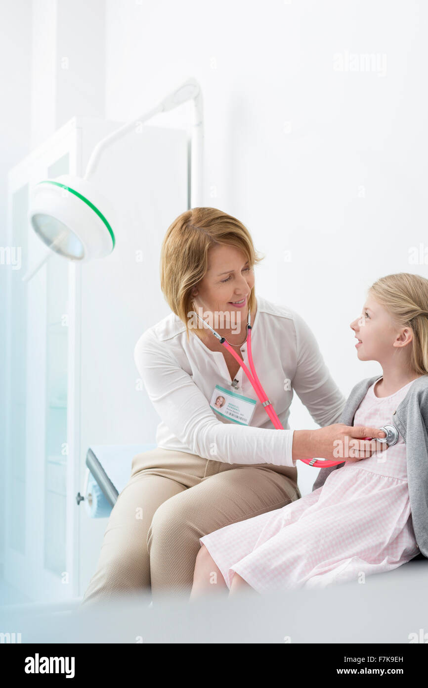 Pediatrician using stethoscope on girl patient in examination room