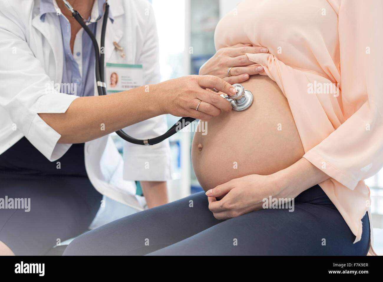 Doctor using stethoscope on pregnant patient’s stomach Stock Photo