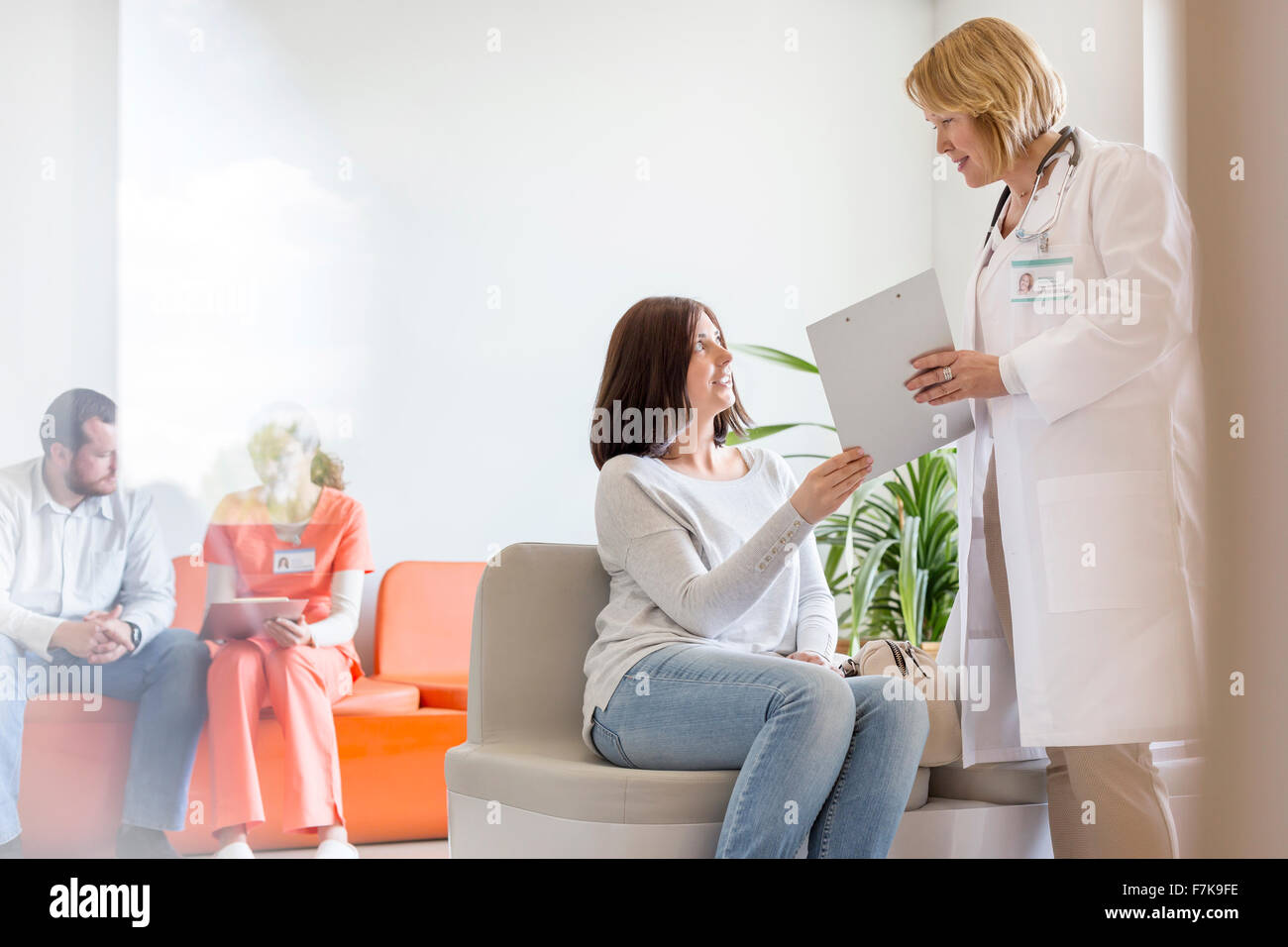 Doctor with clipboard talking to patient in clinic lobby Stock Photo