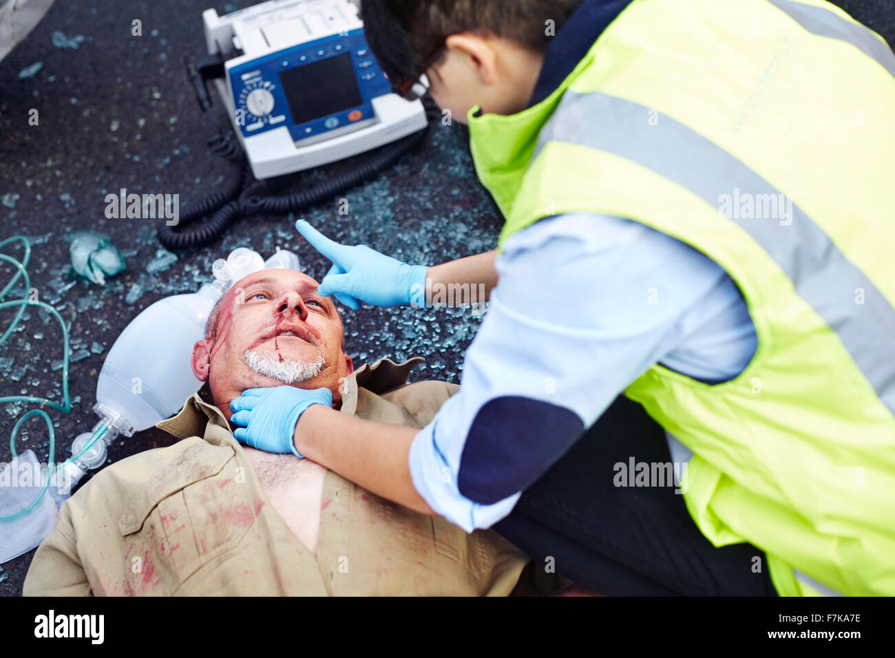 Rescue worker tending to car accident victim in road Stock Photo