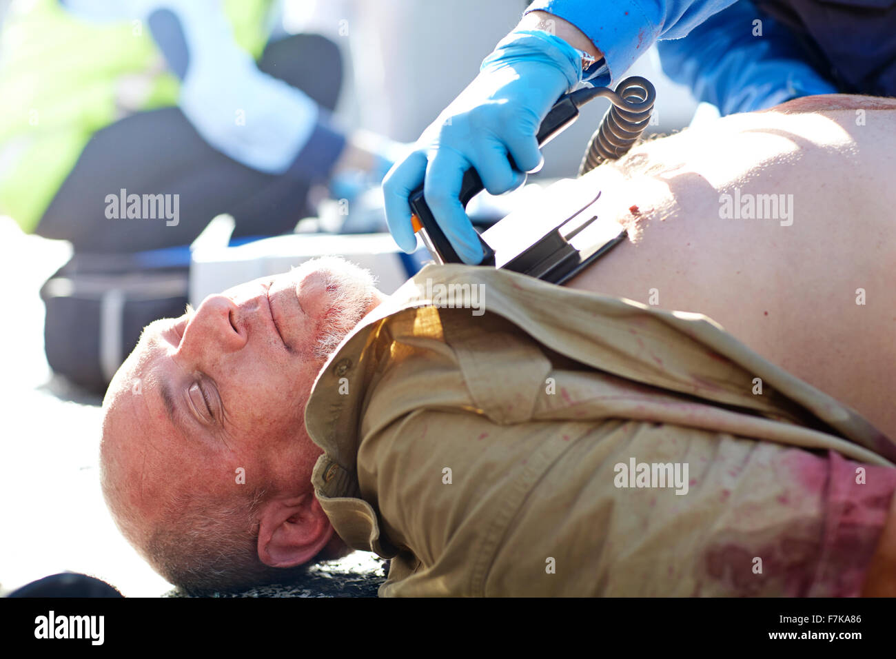 Rescue worker using defibrillator on unconscious car accident victim Stock Photo