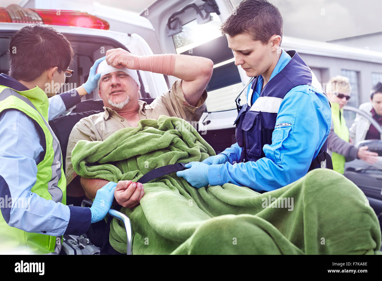 Rescue workers tending to car accident victim on stretcher at back of ...