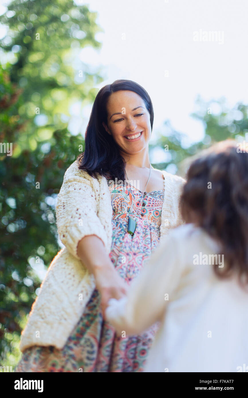 Smiling mother and daughter holding hands outdoors Stock Photo - Alamy
