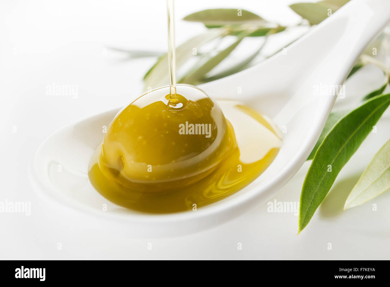 Virgin olive oil pouring on white spoon. Stock Photo