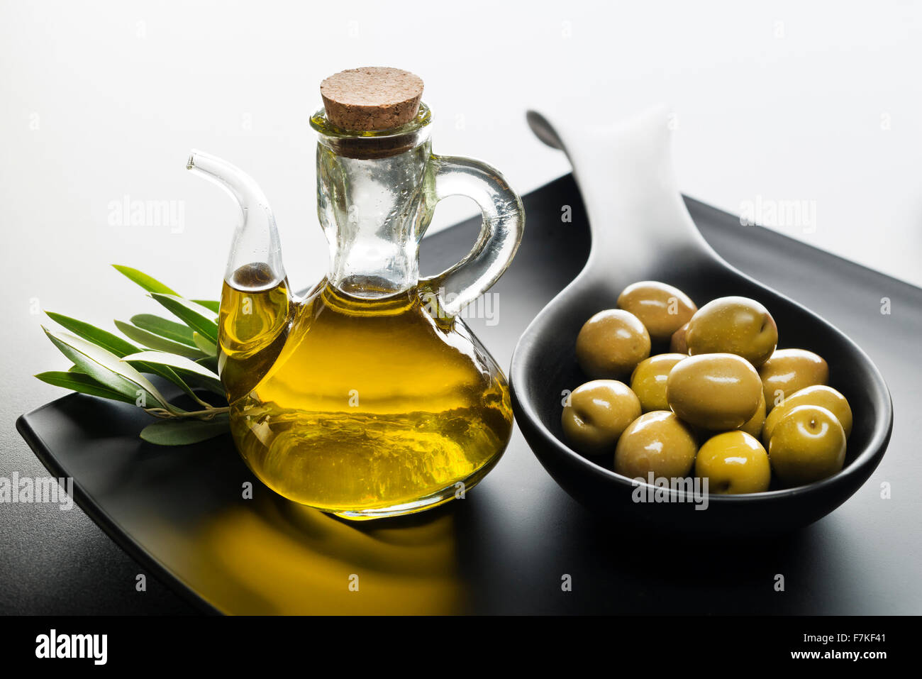 Bottle of premium virgin olive oil and some olives with leaves Stock ...