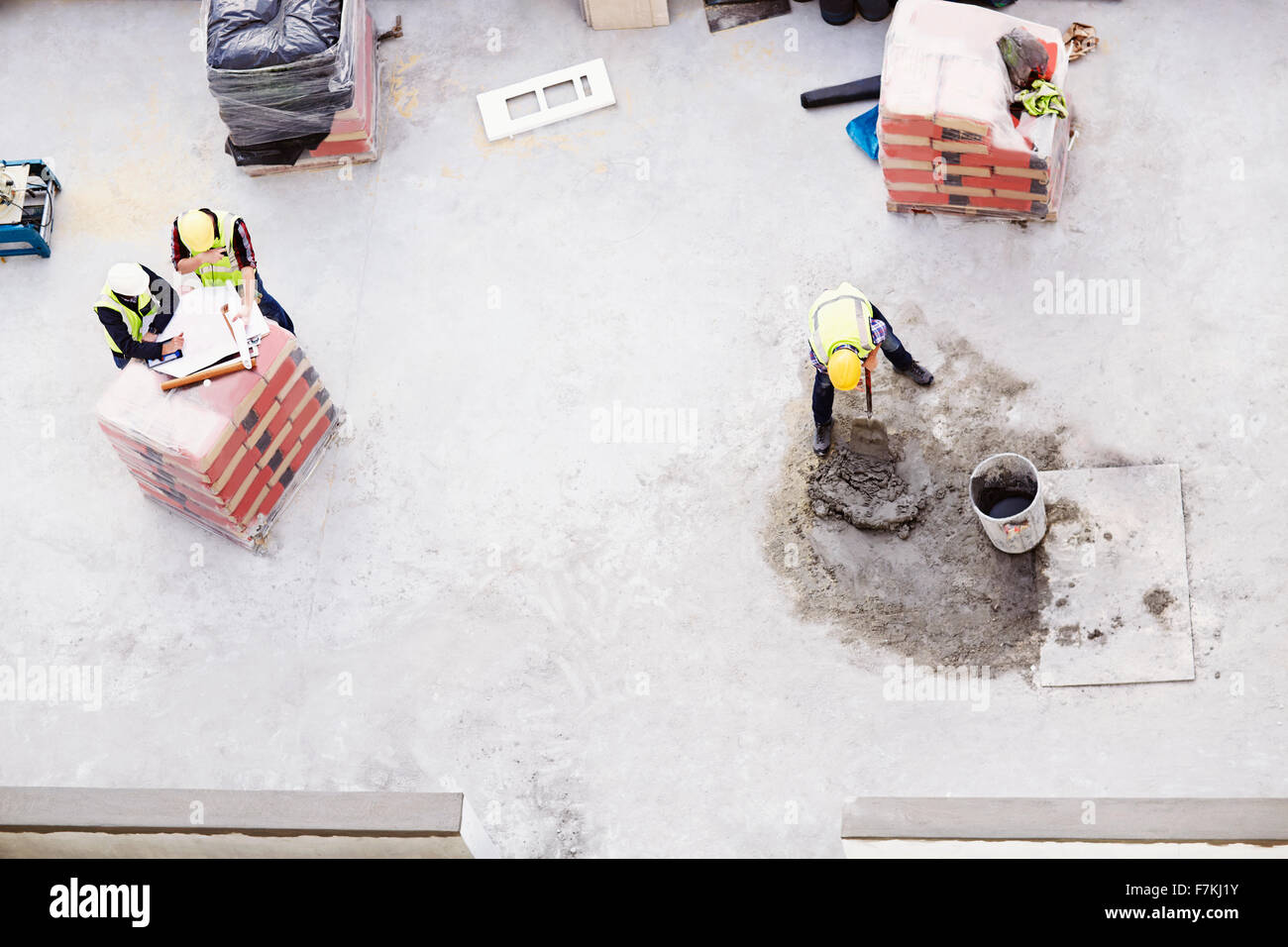 Overhead view of construction workers laying concrete at construction site Stock Photo