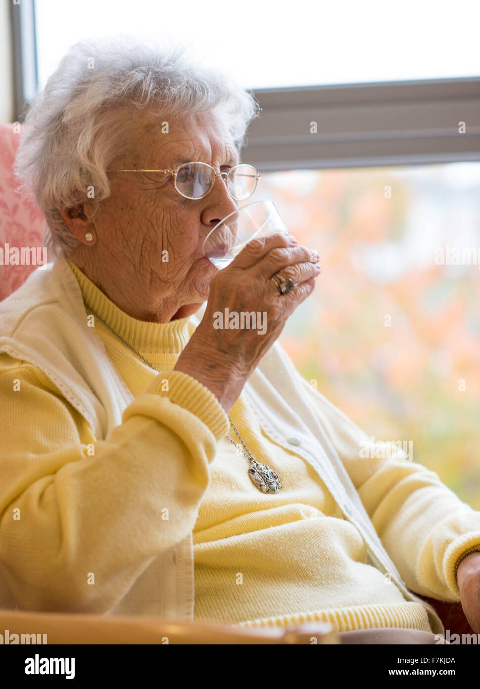 An old lady having a glass of water in an old folks home. Stock Photo