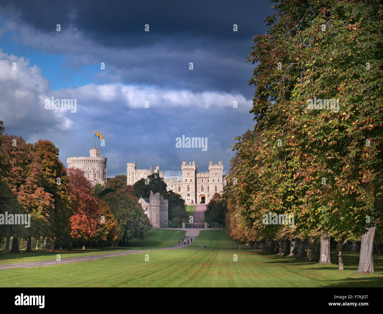 Windsor Castle flying Royal Standard viewed down the Long Walk with walkers, in autumnal colour with dramatic shafts of sunlight and sky Berkshire UK Stock Photo