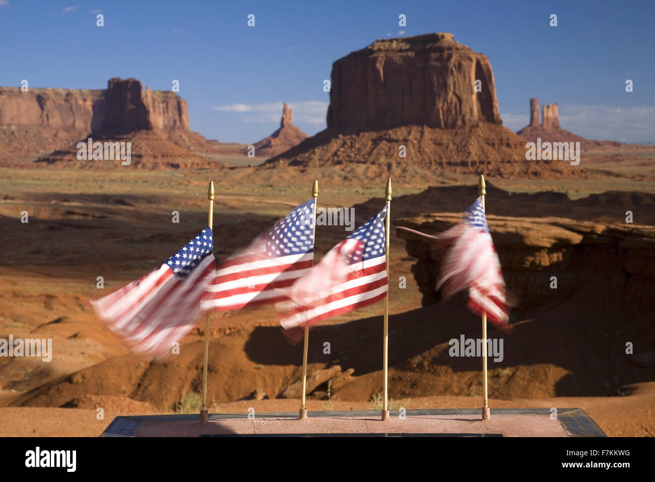 US Flags blowing in wind in front of red buttes and colorful spires of Monument Valley Navajo Tribal Park, Southern Utah near Arizona border Stock Photo
