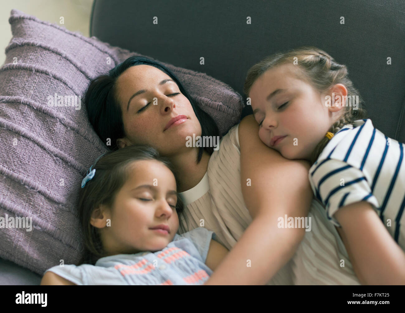 Serene mother and daughters napping on sofa Stock Photo