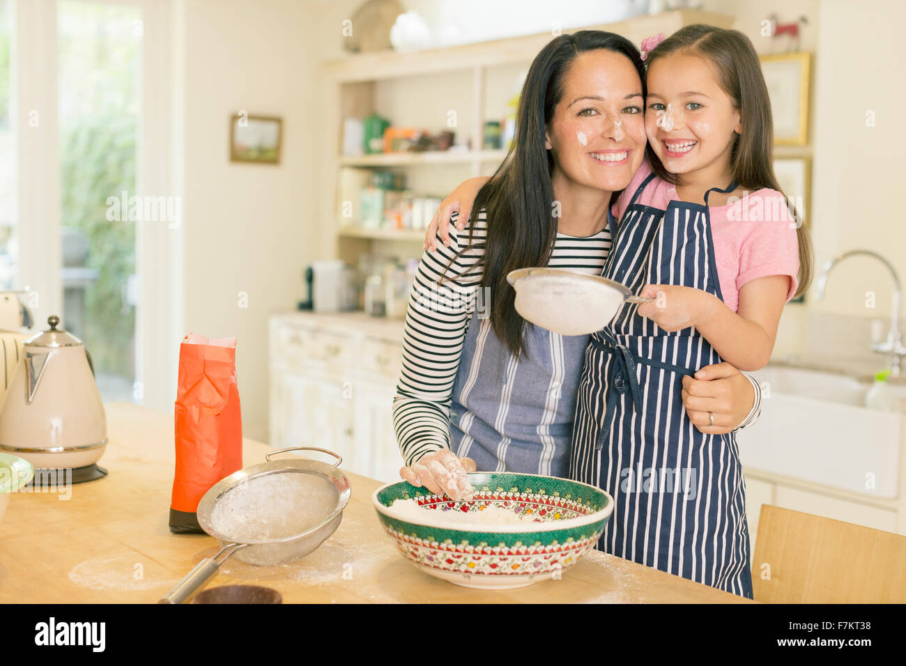 Portrait playful mother and daughter baking in kitchen with flour on faces Stock Photo
