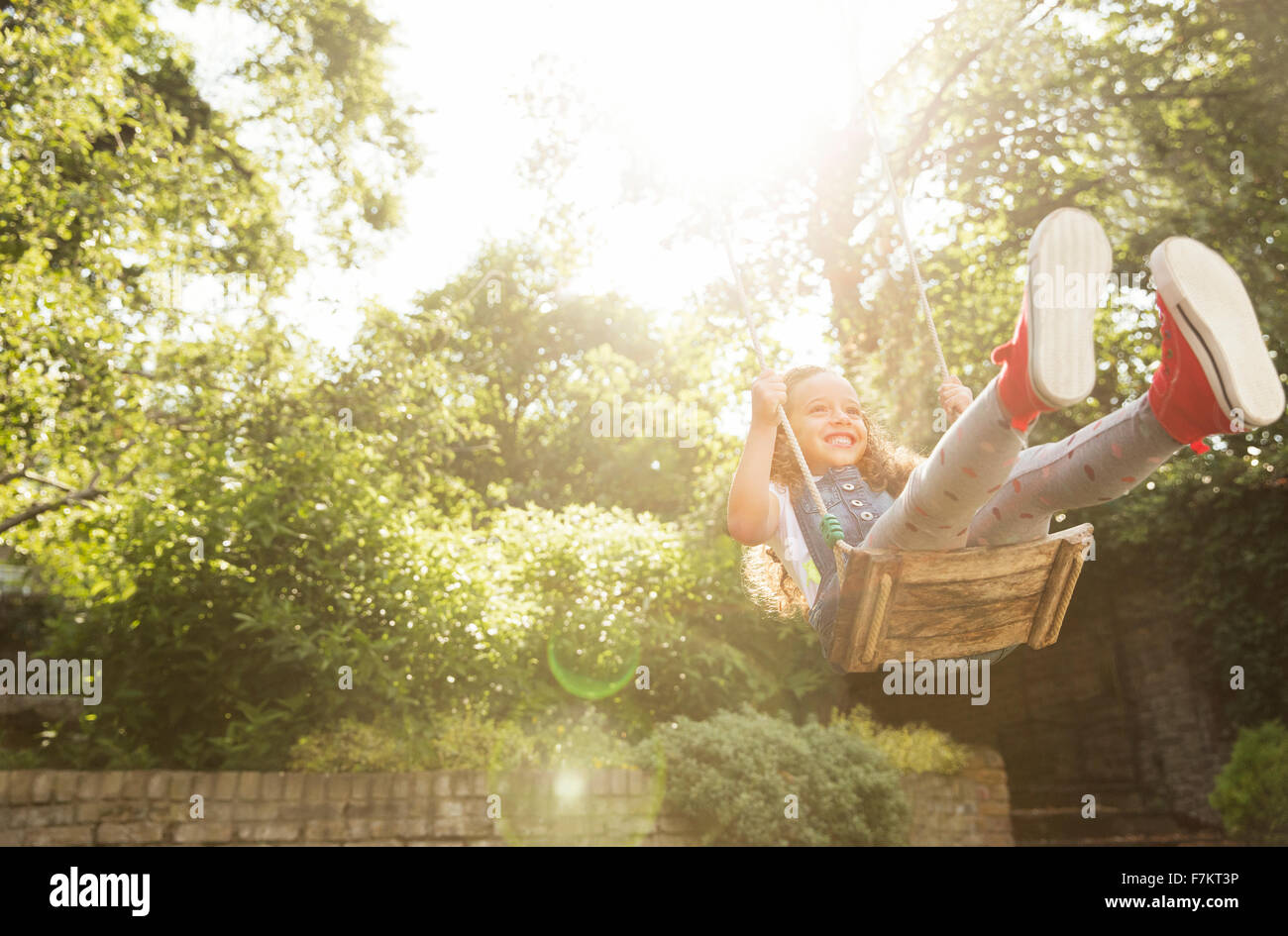 Carefree girl swinging in sunny backyard Stock Photo