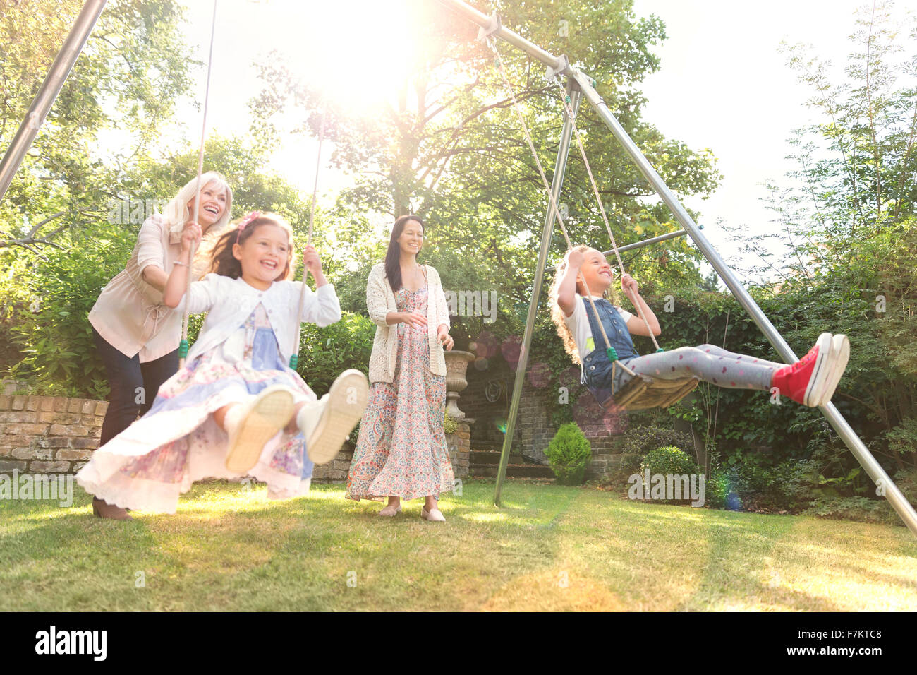 Carefree multi-generation women swinging in backyard Stock Photo