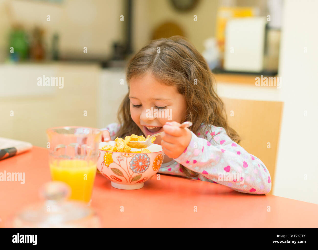 Girl eating cereal at breakfast table Stock Photo