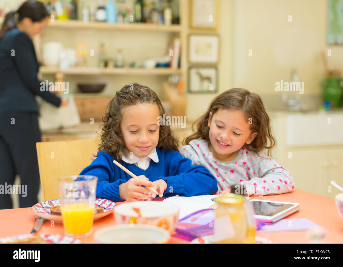 Girls doing homework at breakfast table Stock Photo