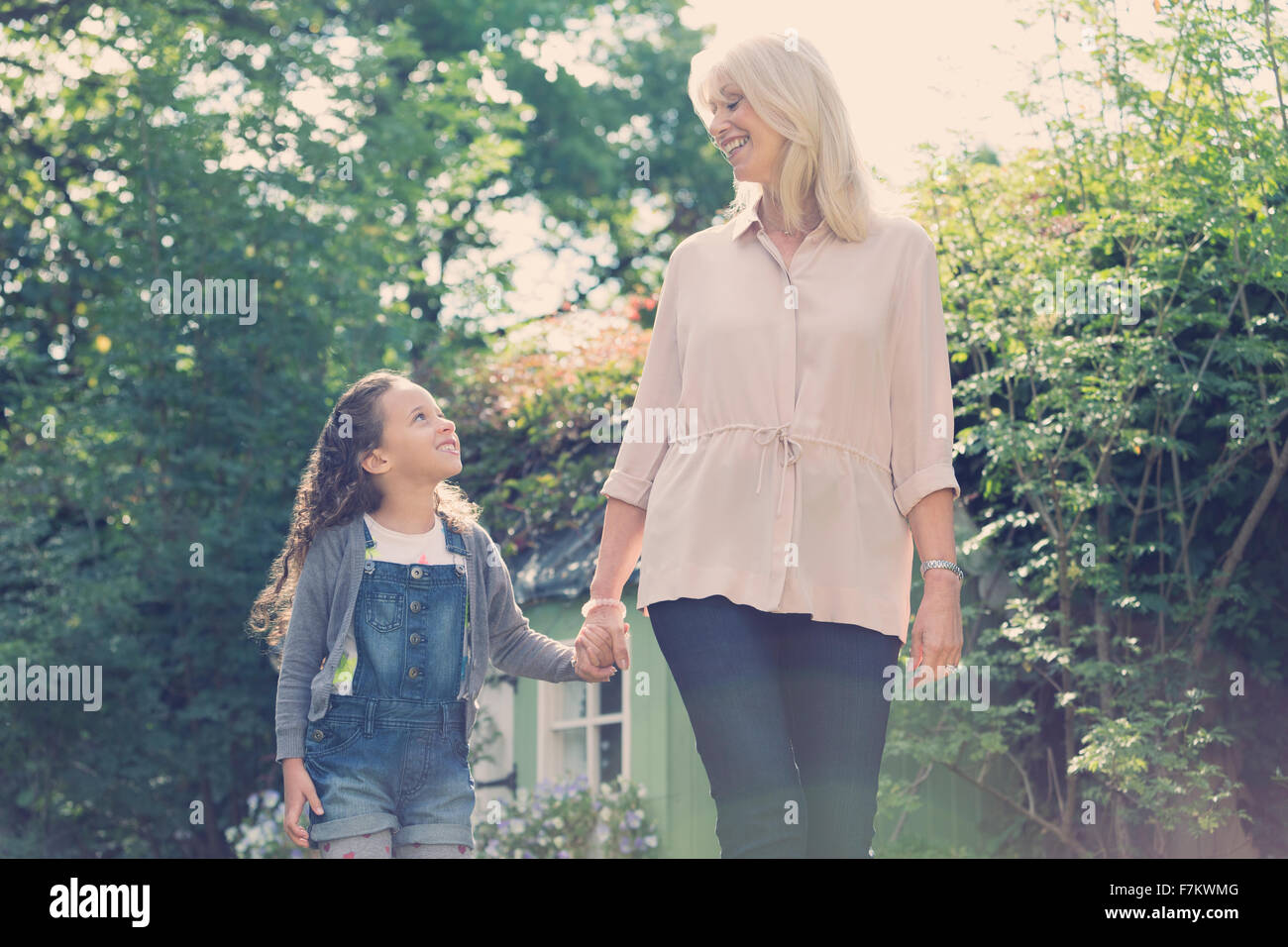 Grandmother and granddaughter holding hands and walking in garden Stock Photo