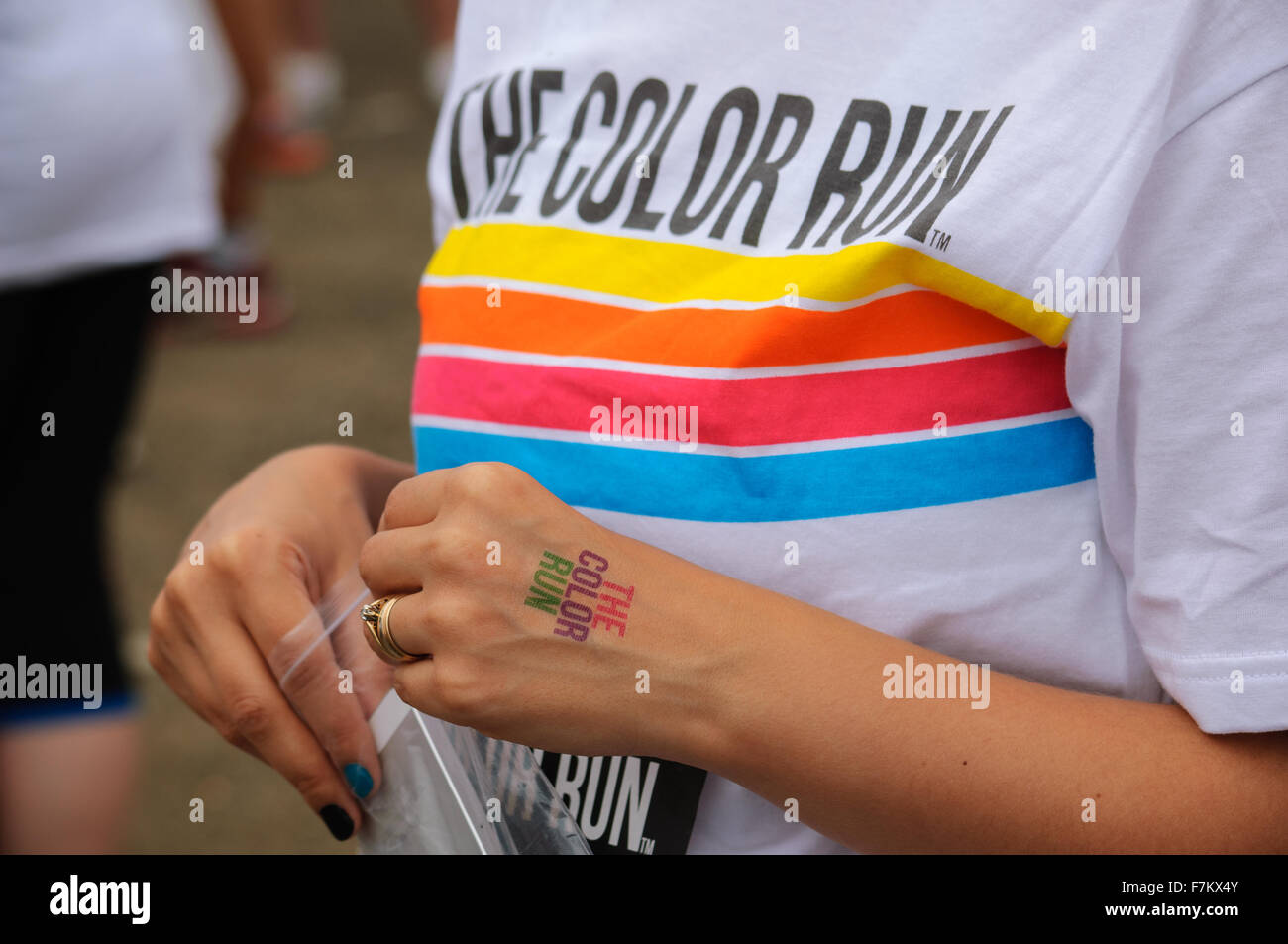 A female competitor wearing a Color Run t-shirt with a temporary tattoo (transfer) on the back of her hand at the 5K Color Run Stock Photo - Alamy