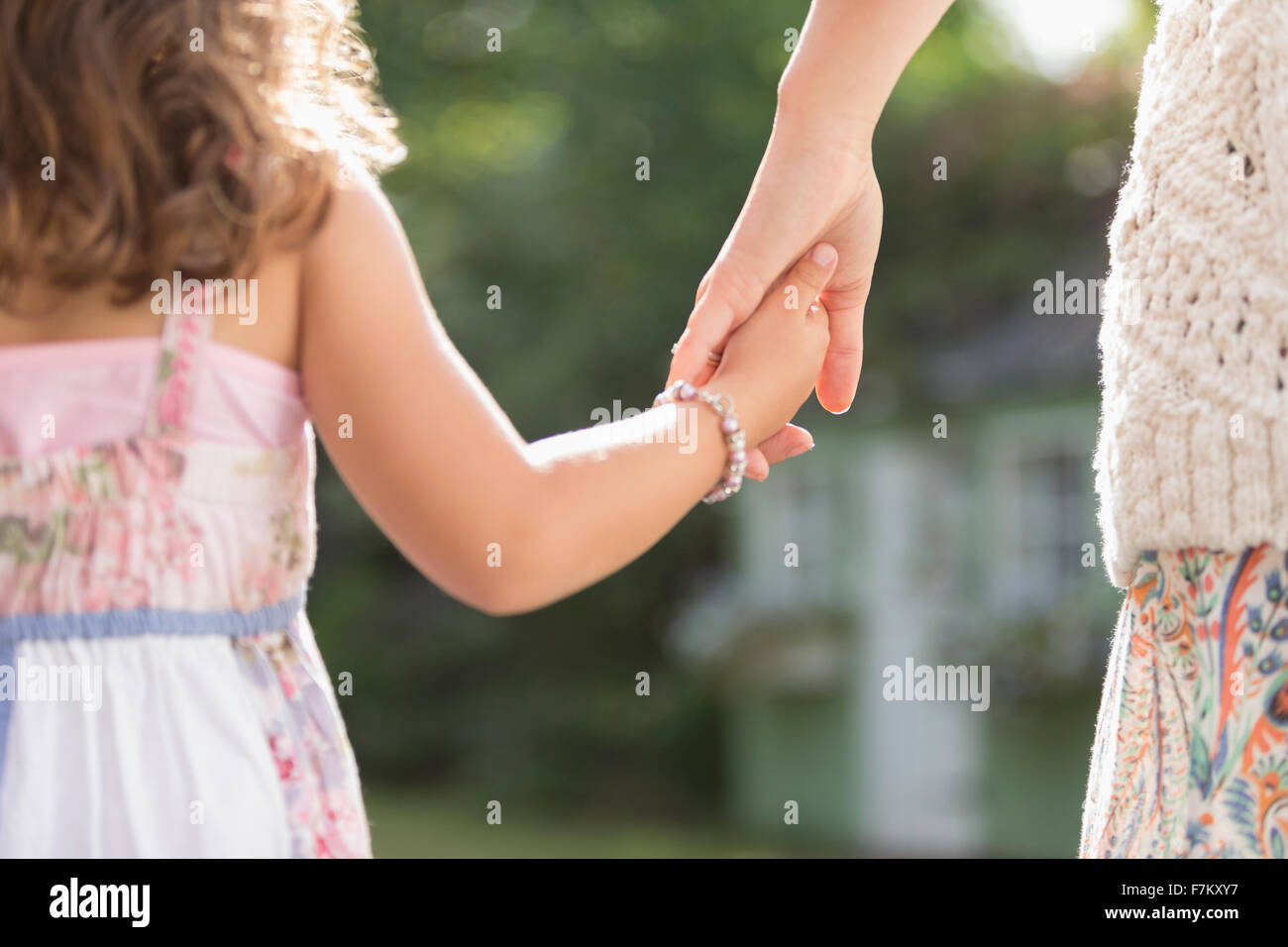 Close up rear view mother and daughter holding hands Stock Photo