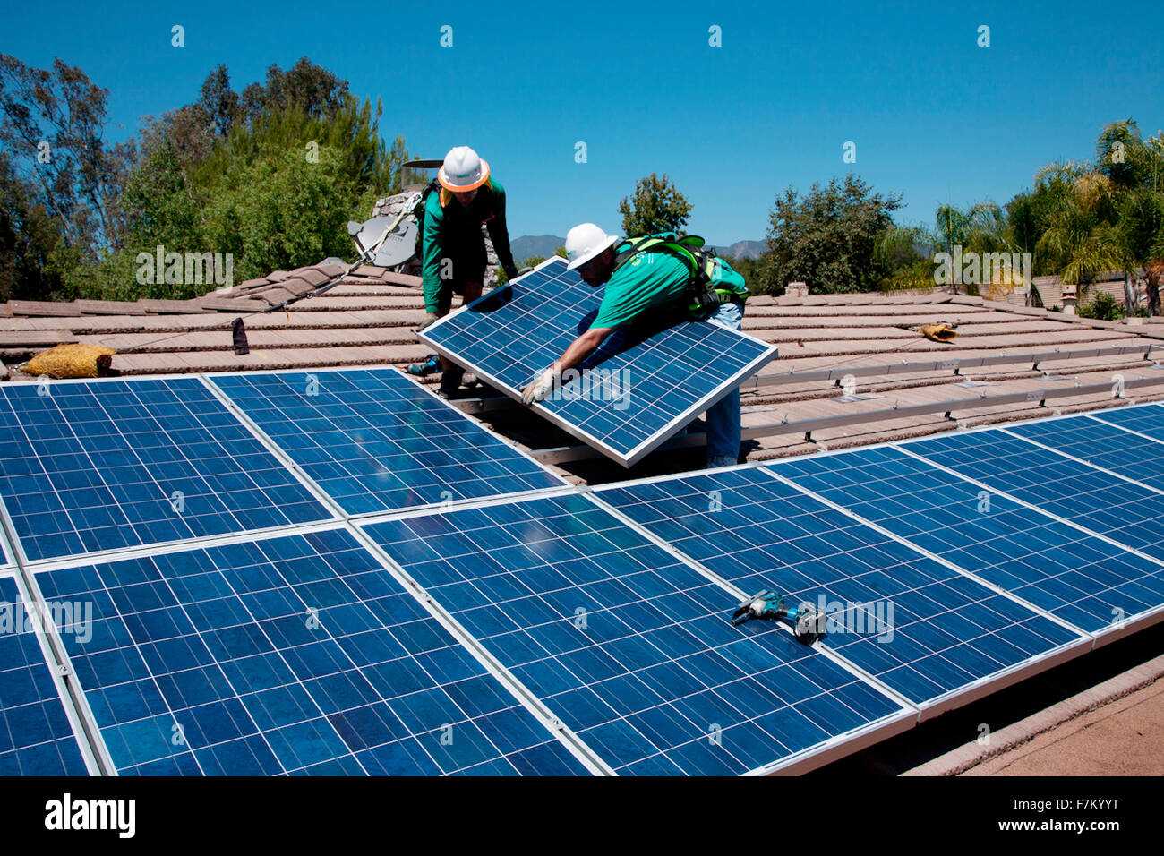 Two male solar workers install solar panels on home in Oak View, Southern California Stock Photo