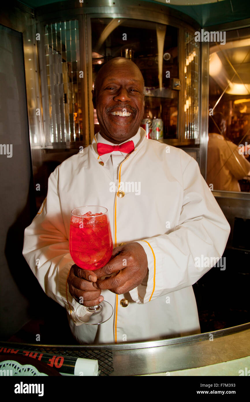 African American Porter reenactor pours cherry soda on Pearl Harbor Day Troop train reenactment from Los Angeles Union Station to San Diego Stock Photo