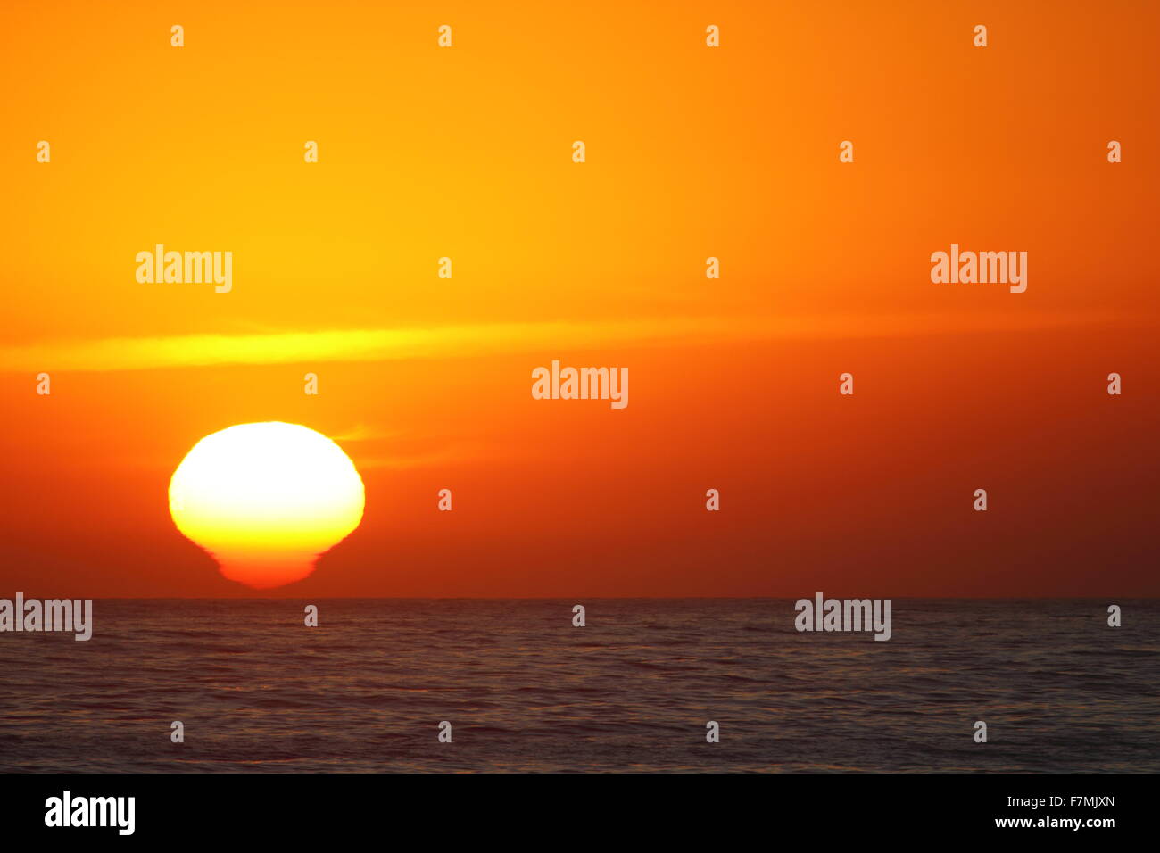 A golden sunrise over the Pacific Ocean; the sun appearing not as an orb but more like a screw-in light bulb. Stock Photo
