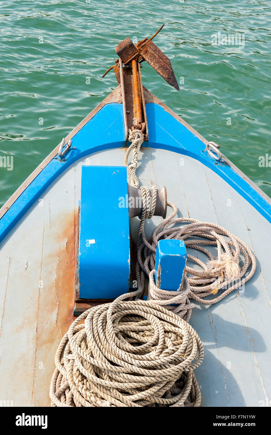 Rusty anchor on the front of a blue wooden boat Stock Photo