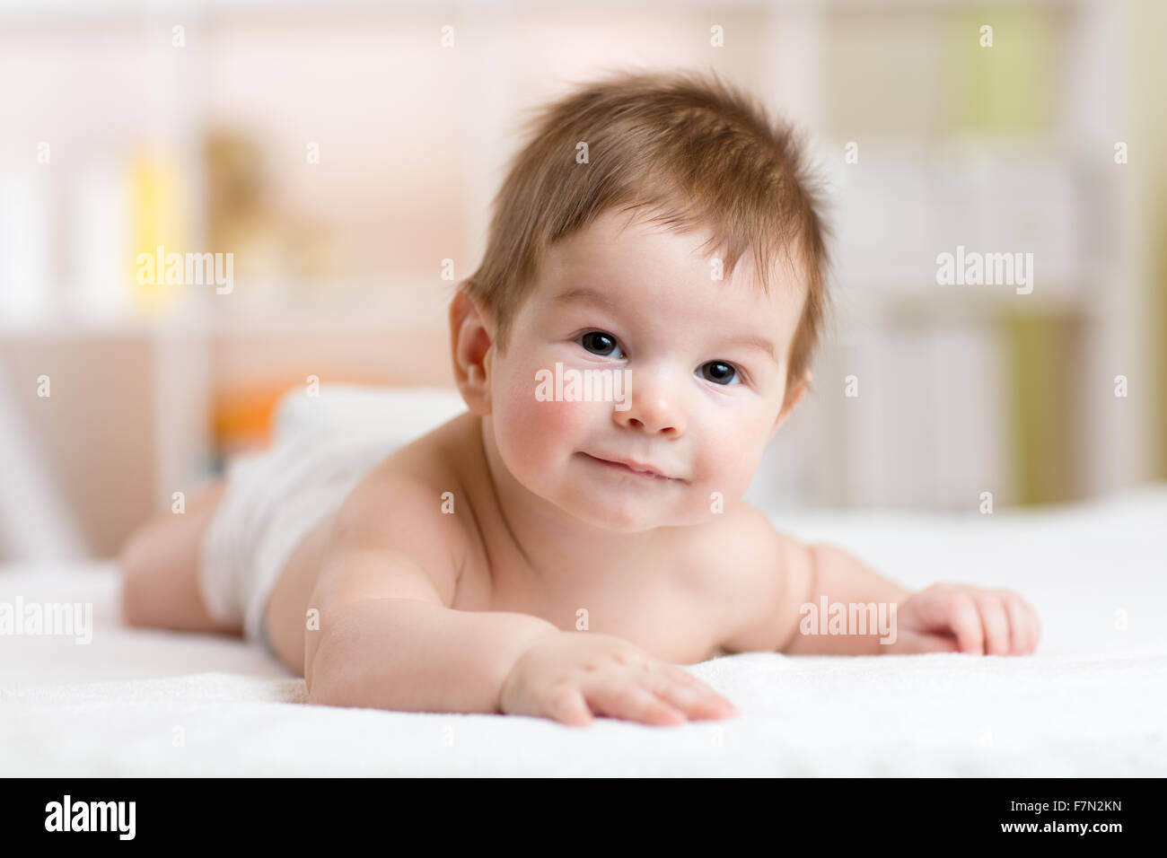 Portrait of a three months old baby on the bed in nursery room Stock