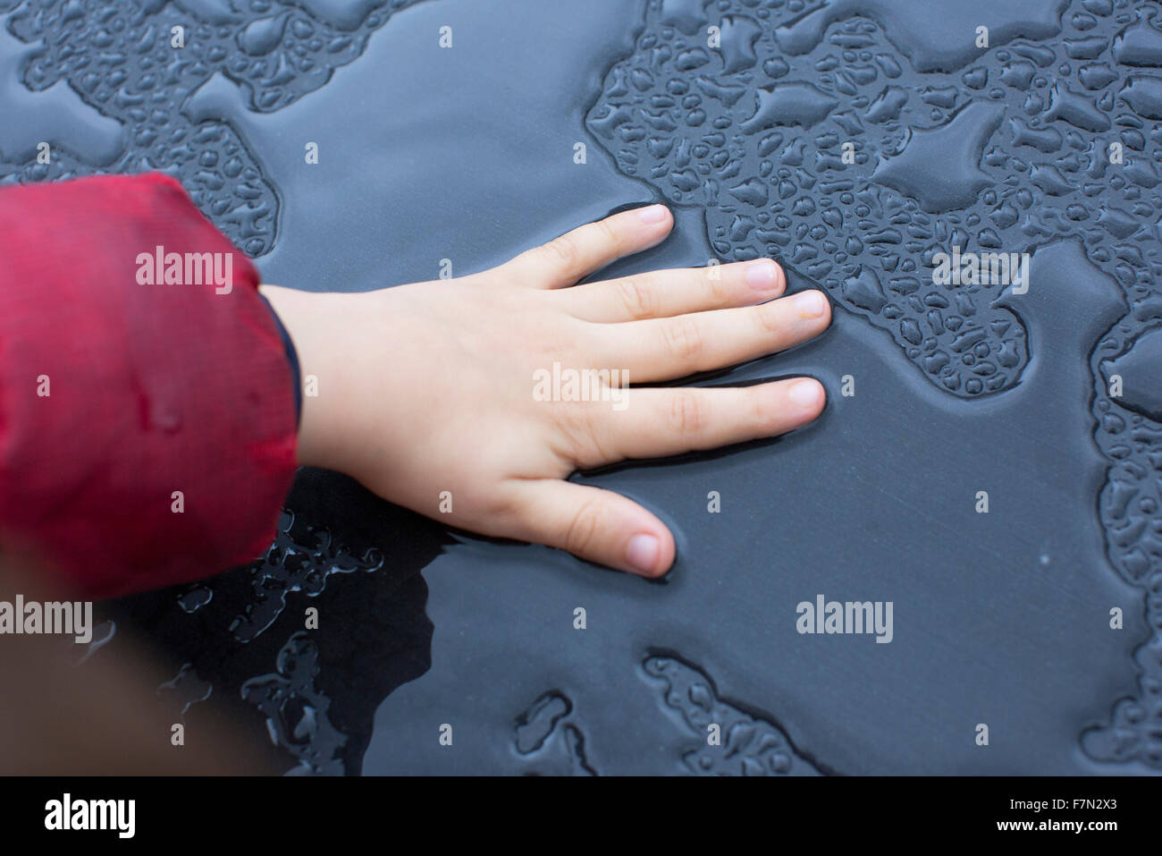 Child touching wet metallic surface Stock Photo