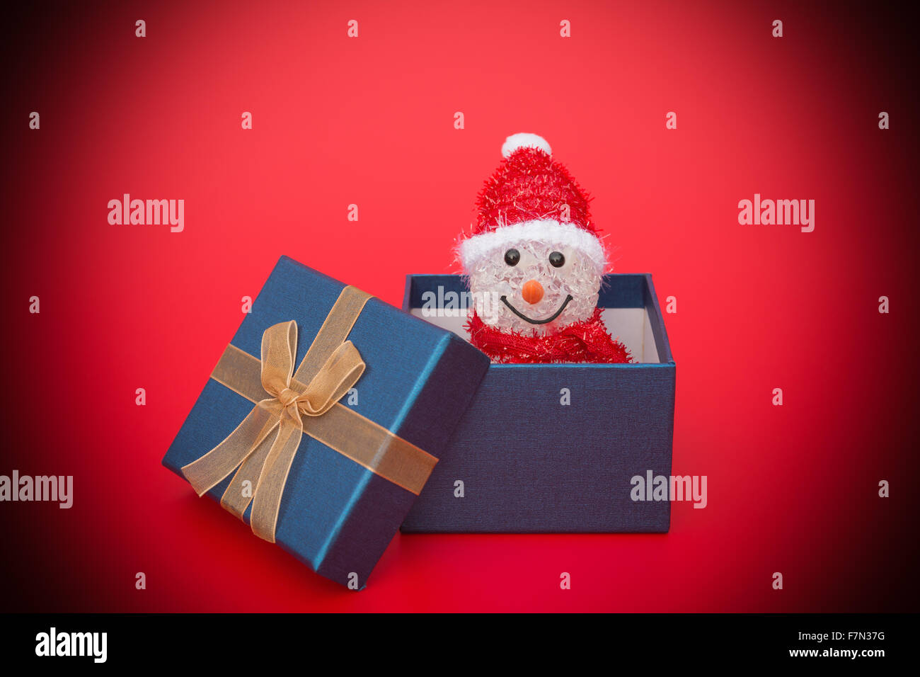 smiling toy christmas snowman in a present box on red Stock Photo
