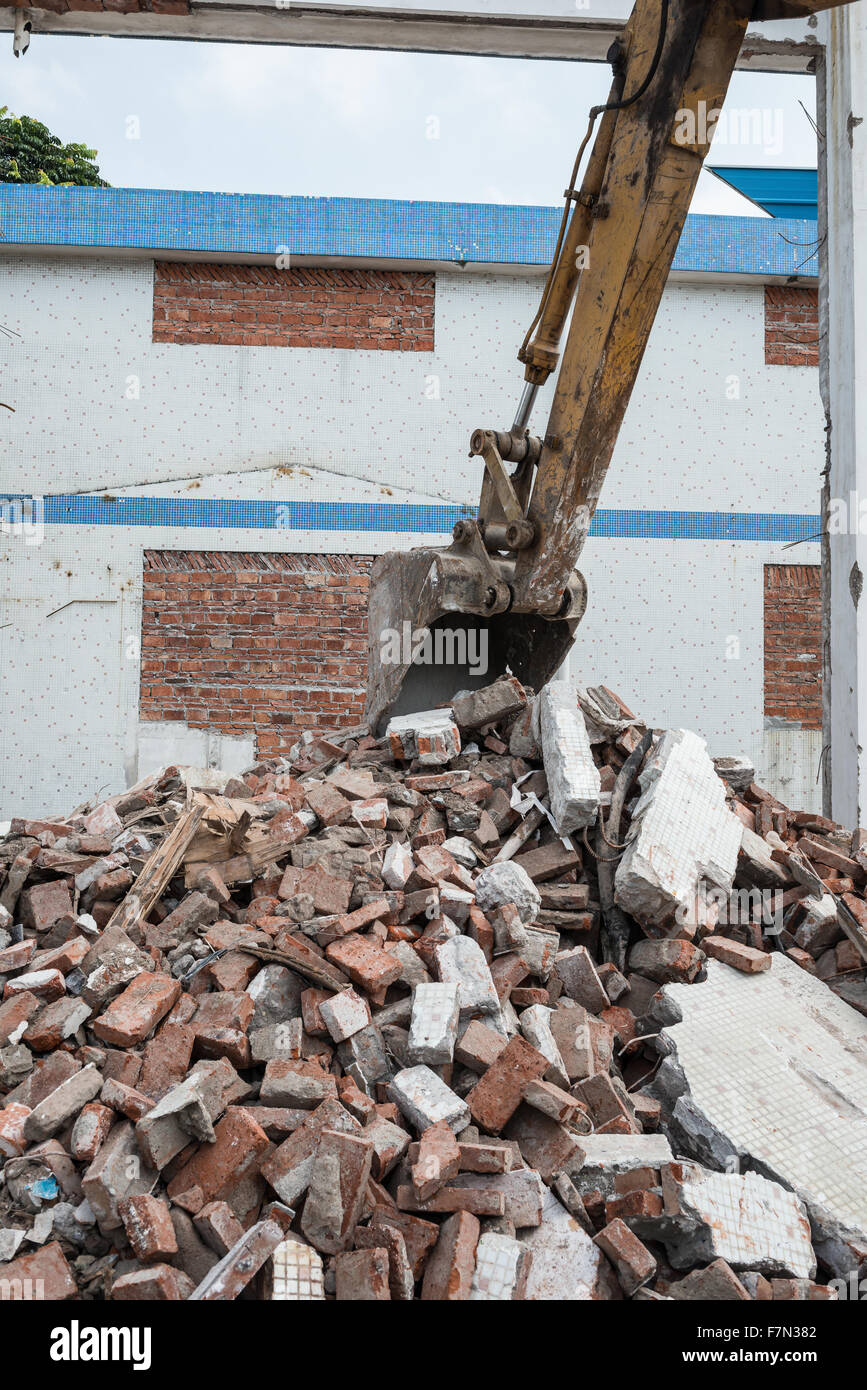 excavator demolishing concrete and brick rubble debris vertical Stock Photo