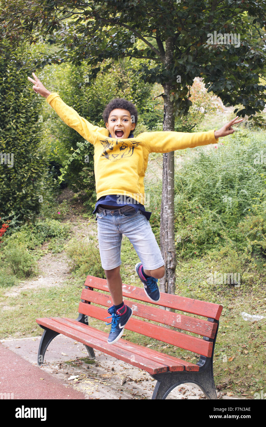Boy jumping off bench Stock Photo