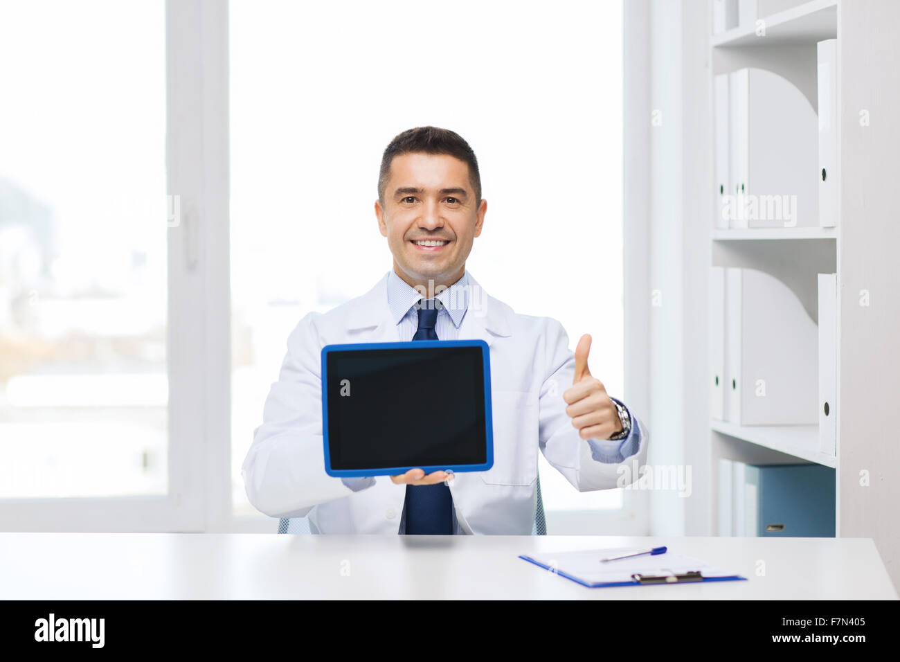smiling doctor showing tablet pc and thumbs up Stock Photo - Alamy