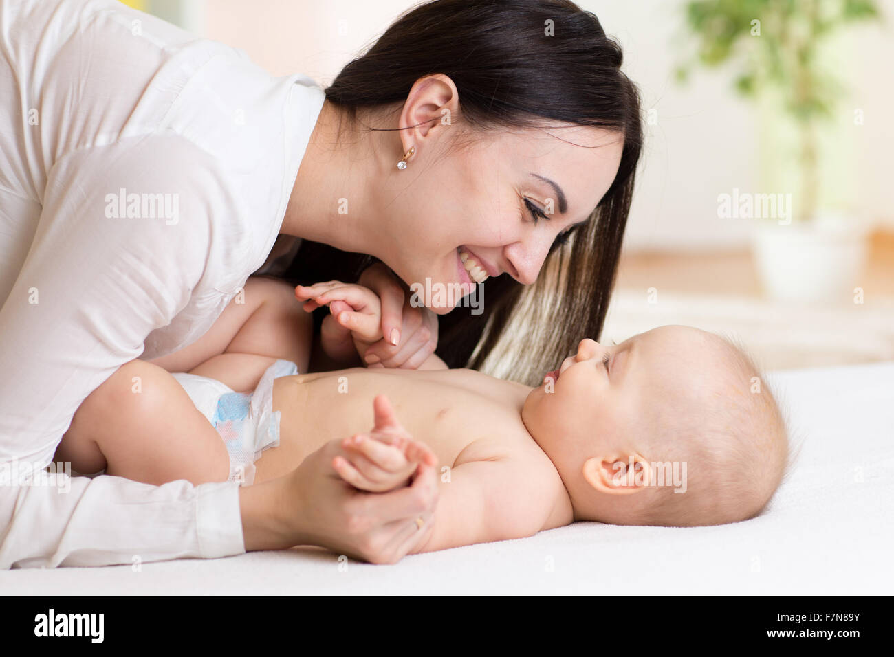 Happy mother looking at baby in bedroom Stock Photo