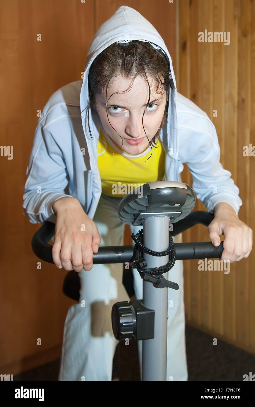 Young girl in   sportswear exercising on exercise bike Stock Photo