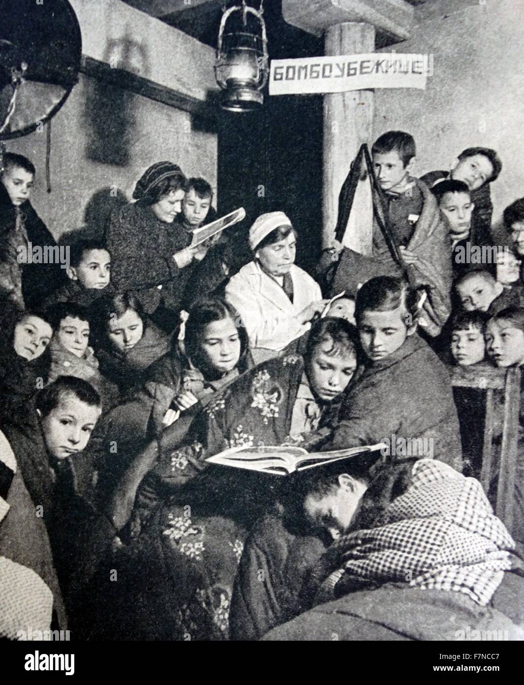 Bomb Shelter' says the notice on the pillar supporting the roof of this basement where children are gathered during one of Leningrad's frequent air raids alerts. Stock Photo