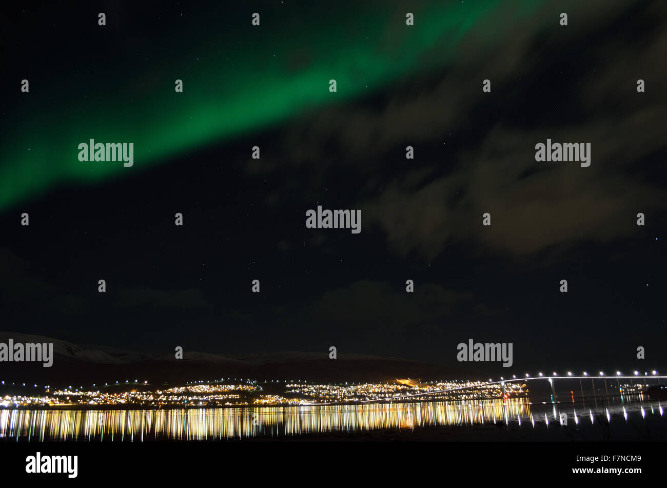 aurora borealis over arctic circle settlement reflecting in fjord water ...