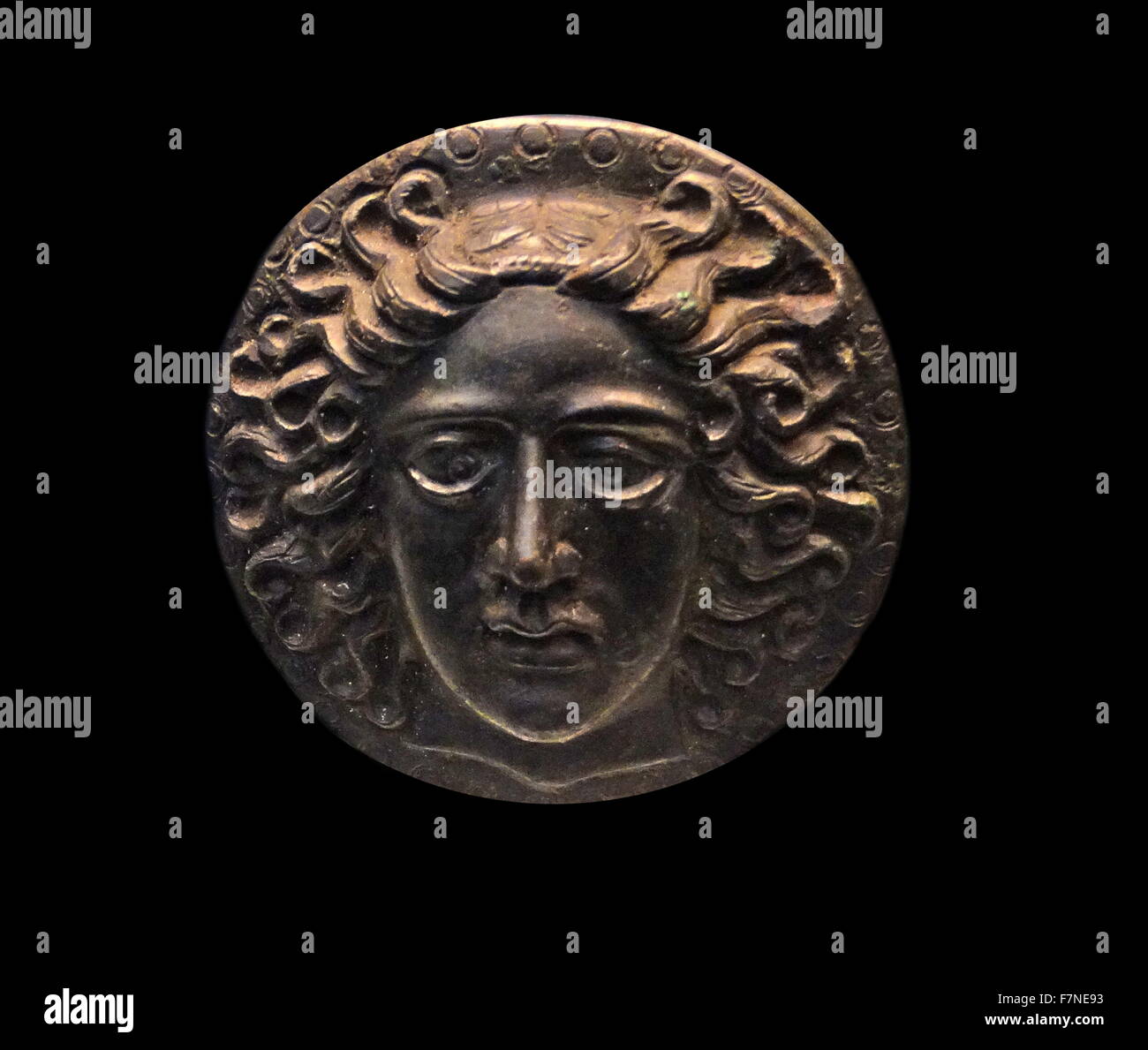 Greek bronze disc, with a head of the sun-god Apollo Helios. 5th-3rd century BC Stock Photo