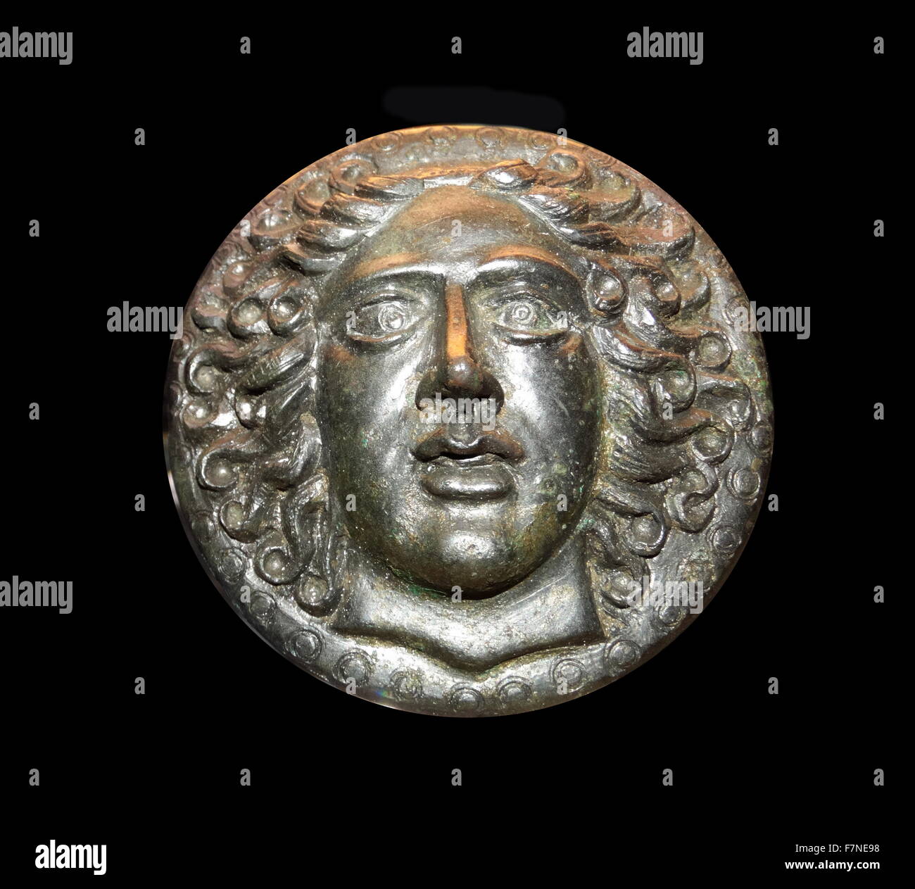 Greek bronze disc, with a head of the sun-god Apollo Helios. 5th-3rd century BC Stock Photo