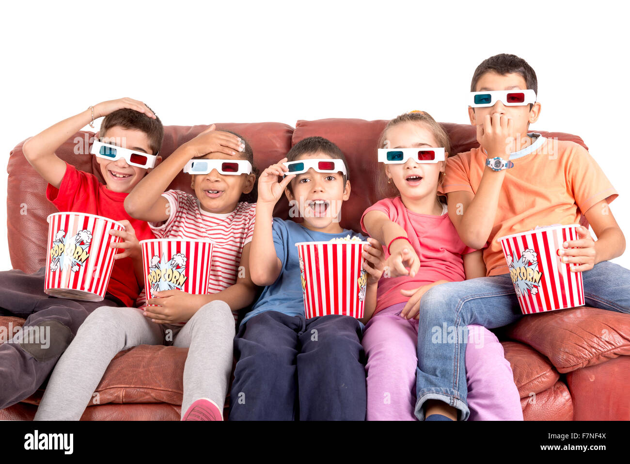 Group of children with 3d glasses and popcorn in a sofa having fun Stock Photo