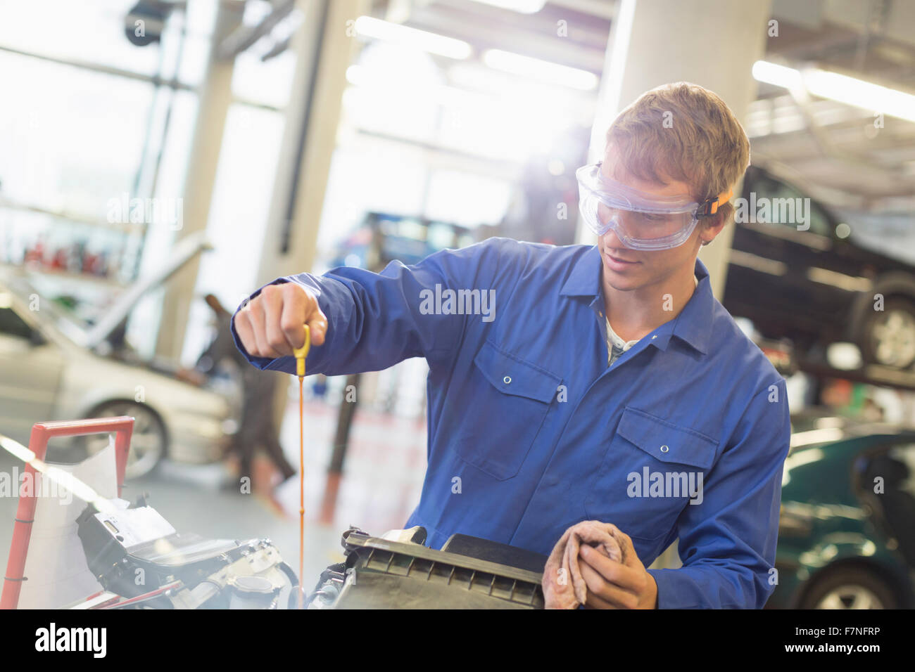 Mechanic checking engine oil in auto repair shop Stock Photo - Alamy