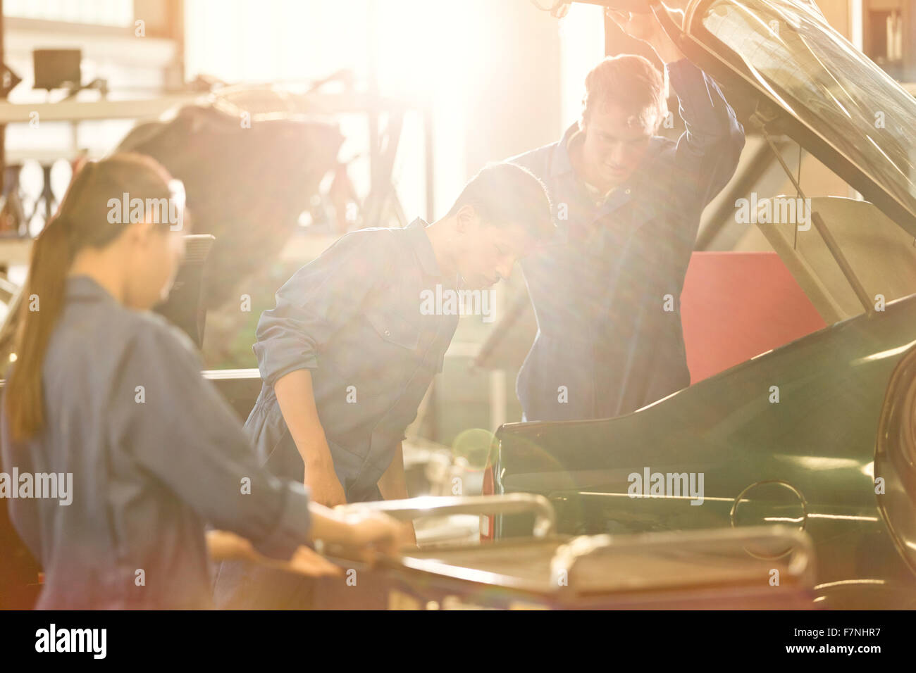 Mechanics looking inside trunk in auto repair shop Stock Photo Alamy