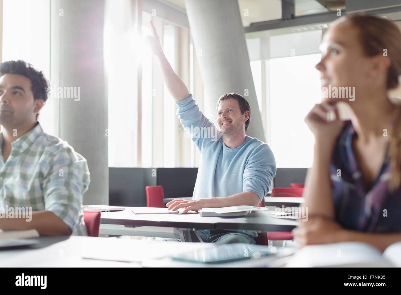 Eager man raising hand in adult education classroom Stock Photo