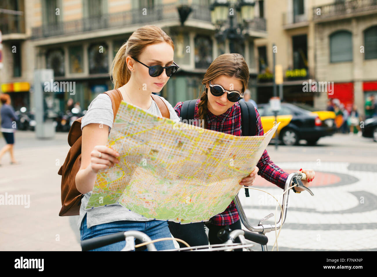 Spain, Barcelona, two young women with map on bicycles in the city Stock Photo